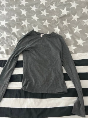 Grå långärmad topp från nelly - En enkel och stilren grå långärmad topp från Nelly.. Toppen har en rund halsringning och är tillverkad i ett mjukt bomullsmaterial. Använd ett fåtal gånger 