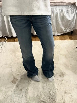 Blå bootcut jeans från Diesel - Säljer ett par blå bootcut jeans från Diesel med slitningar och lätt tvättad look. Jeansen har klassisk femficksmodell och låg midja. Perfekta för dig som gillar en avslappnad och trendig stil. I storlek 16y, passar som storlek 40 typ eventuellt storlek 38