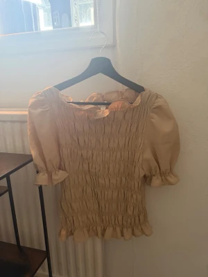 Beige topp - Säljer en mönstrad beige topp med puffiga armar från H&M som inte kommer användning. Endast använd 1 gång💓