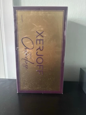 Xerjoff Uden Overdose Parfym 50 ml - Lyxig parfym från Xerjoff, Uden Overdose, i en elegant förpackning med guld- och lila detaljer. Flaskan innehåller 50 ml och doften är intensiv och exklusiv, perfekt för dig som gillar unika och kraftfulla parfymer.