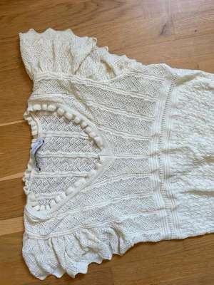 Beige virkad topp med volangärmar - Superfin vit stickad topp med volangdetaljer vid ärmar och halsringning. Toppen har v-ringad hals och ett snyggt mönster i stickningen, perfekt för sommaren🥰.  Stl s, köpt för några år sedan men ej använd