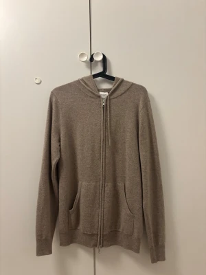 John Henric Kashmir hoodie - Mysig beige hoodie med dragkedja framtill och två fickor med 100% Kashmir. Perfekt för en avslappnad stil och enkel att matcha med andra plagg. Nästintill oanvänd och inga tecken på användning. 