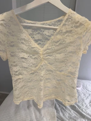 Ljusgul spetsblus med v-ringning - Söt ljusgul blus i spets med korta ärmar och v-ringad hals. Blusen har en snygg rynkning framtill och är genombruten i materialet vilket ger en romantisk vibe. Perfekt att styla med jeans linne kjol för en trendig look. 🥂💛