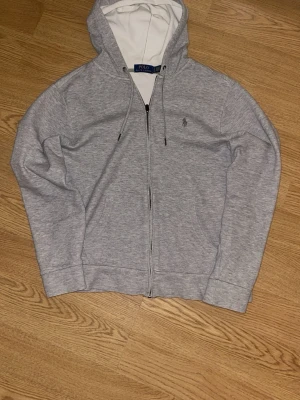 Grå zip hoodie från Polo Ralph Lauren - Jag säljer min gråa Ralph lauren tröja då den inte längre passar, den är storlek s i herr och har inga defekter, andvänd fåtal gånger, priset kan sänkas vid smidig affär 