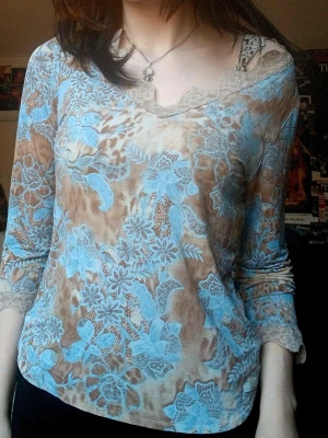 Blommig topp med spetsdetaljer - Säljer en beige och ljusblå blommig topp från claire.dk med v-ringning och spetsdetaljer vid hals och ärmslut. Toppen har lång ärm och är tillverkad i ett tunt, mjukt material som känns skönt mot huden. Perfekt för dig som gillar romantisk och bohemisk stil. Passar xs-m (jag är xs/s)