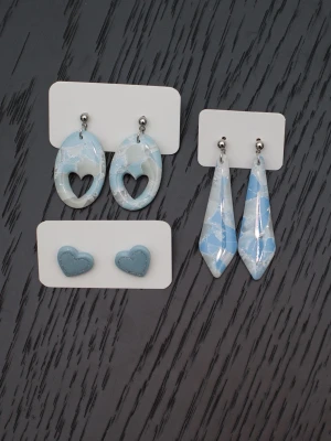 Handgjorda örhängen i polymerlera och stift i rostfritt stål hjärta ljusblå  - Handgjorda örhängen i polymerlera och stift i rostfritt stål.  Självklart nya och oanvända. Storlek: Ovala med hjärtan 2x4cm. Avlånga 1,5x5,5cm. Små hjärtan (stiftörhängen) 1,5x1,5cm.  Färgerna kan variera beroende på skärminställningar.