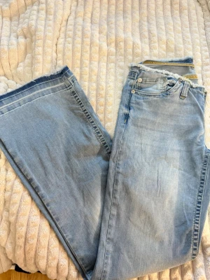 Ljusblåa vida jeans med råa kanter - Säljer ett par ljusblå jeans med riktigt breda ben och råa, fransiga kanter både vid midjan och bensluten. Jeansen har klassisk femficksdesign och är gjorda i mjuk denim. Perfekta för en avslappnad och trendig look. Slutsålda i nellys hemsida köpta för 559kr. 