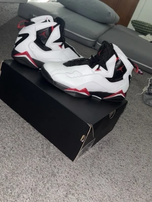 Jordan True Flight White/ Varsity Red/ Black - Snygga Air Jordan sneakers i vitt och svart med röda detaljer. Skorna har högt skaft, klassisk Jumpman-logga på plösen och robust sula. Ovandelen är i läder och mesh för bra komfort och stil. Perfekta för dig som vill sticka ut med en ikonisk look. Funkar bra för basket. Och en massa andra idrotter passar även bra med jeans