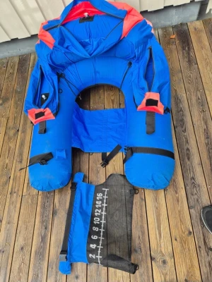 Blå flytring med förvaringsfickor - Säljer en blå och orange flytring med flera dragkedjeförsedda förvaringsfickor och justerbara remmar. Tillverkad i slitstark nylon och mesh, med en avtagbar mätbräda för fisk. Perfekt för fiske eller chill på vattnet. Rund form och tydliga detaljer för enkel användning.