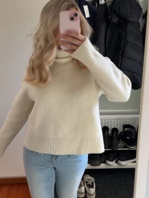 Vit polotröja i stickat - Klassisk vit stickad polotröja med breda ribbade muddar vid ärmslut och nederkant. Tröjan har en hög polokrage och rak passform, perfekt för en clean och enkel look. Passar till jeans💞💞Nypris 600kr. Endast använd en gång!