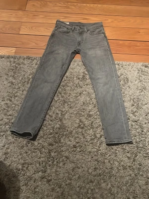 Levi's 502 - Säljer ett par grå jeans från Levi's med klassisk femficksmodell och raka ben. Jeansen är. tillverkade i bomull med en skön passform som funkar till det mesta.                                                        W28 L30.                                                        Andvända en gång