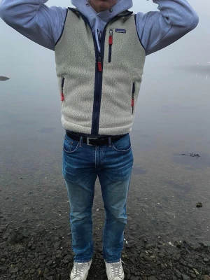 Beige fleeceväst från Patagonia - Säljer en beige fleeceväst från Patagonia med marinblå detaljer och röda dragkedjor. Västen har tre fickor med dragkedja. 