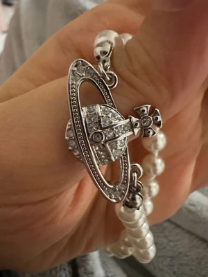  Silver pärlarhalsband  - Snyggt halsband med vita pärlor och det ikoniska Orb-hänget i silverfärgad metall med glittrande stenar. Perfekt statement-piece för dig som gillar unika accessoarer och cool design.