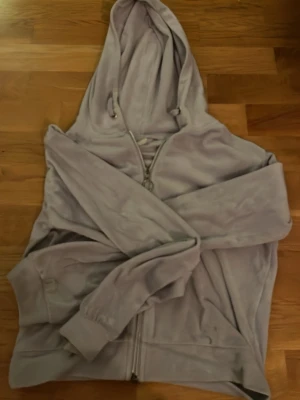 Ljuslila hoodie med dragkedja - Mysig ljuslila hoodie med dragkedja framtill och huva med dragsko. Tillverkad i mjukt, fleeceliknande material och har ribbade muddar vid ärmsluten. Perfekt för en avslappnad och chill stil.