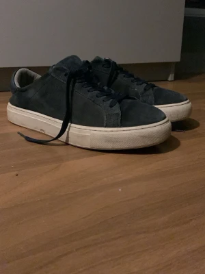 Mörkblå mockasneakers med vit sula - Stilrena sneakers i mörkblå mocka med klassisk låg profil och tjock vit sula. Skorna har matchande mörkblå skosnören och en enkel, minimalistisk design som passar till det mesta. Perfekta för dig som gillar en clean look och vill ha något som funkar året runt.