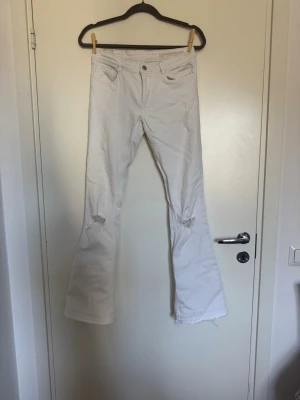 Vita bootcut jeans med slitningar - Säljer ett par lågmidjade bootcut jeans från Zaras jätte gamla kollektion. Dom är i fint skick förutom att dem har en lite fläck vid rumpan men går bort om man skrubbar med galltvål. Men det syns verkligen inte mycket!