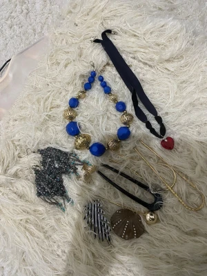 Smycke och håraaccesoar alla för 40kr - Unikt halsband med stora blå och guldfärgade pärlor i plast och metall. Halsbandet har en iögonfallande design med varierande storlek på pärlorna och ger en cool statement-look. Perfekt för dig som vill sticka ut med accessoarerna.