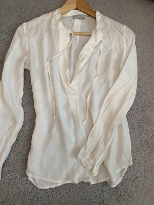 Vit blus med knytband från InWear - Stilren vit blus från InWear i storlek 36. Blusen har långa ärmar, v-ringning med knytband och är tillverkad i ett lätt och mjukt tyg