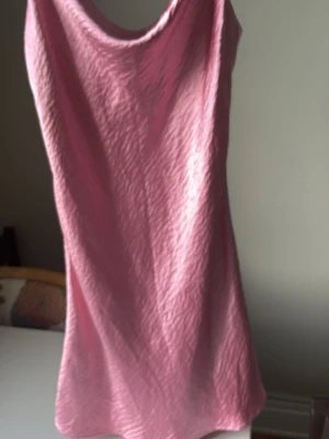 Rosa ärmlös kortklänning - Säljer en  rosa kortklänning i ett silkeslikt material.