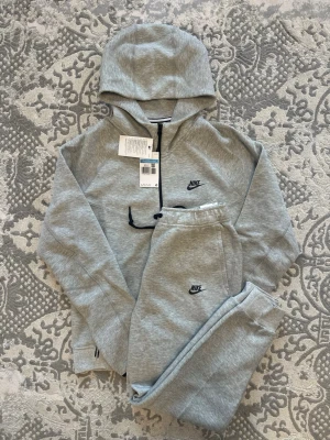 Nike Tech Fleece Tracksuit - Grå M - Grå Nike Tech Fleece Tracksuit i storlek M. Helt ny och oanvänd. Taggarna är fortfarande på och är i perfekt skick. Pris kan diskuteras. 