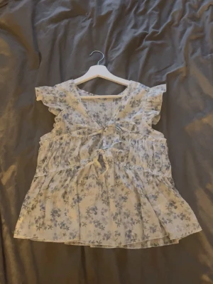 Blommig volangblus med knyt - Söt blus med ljusblått blommönster. Perfekt till sommaren💕💕 passar xs & s. Kom privat vid intresse eller fler bilder💕💕toppen skick!!
