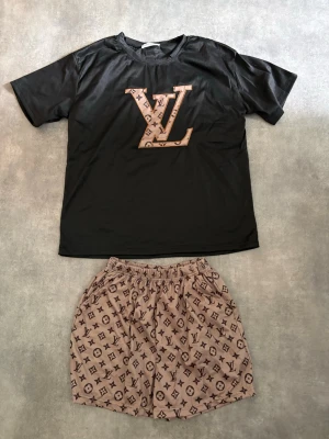 Short och t-shirt - T-shirt och shorts med tryck på. Svart med guldig färg. Fickor fram på shortsen. Resår i midjan på shortsen, väldigt stretchiga. Köpt som storlek S hela setet. Passar även en M, beroende på kroppstyp såklart. Aldrig använt!