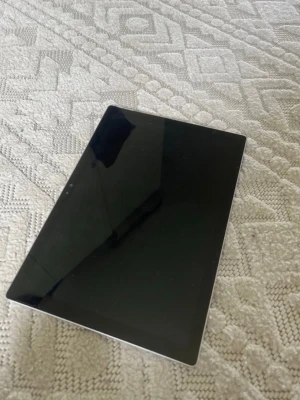 Microsoft Surface bärbar dator - Säljer en stilren och tunn Microsoft Surface med silverfärgat metallskal och stor svart pekskärm. Perfekt för dig som vill ha en smidig laptop som även funkar som surfplatta. Klassisk Surface-design med Microsoft-logga på baksidan. Liten spricka på sidan (bild fem). Tangentbord och mus ingår!