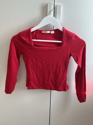 Röd långärmad topp Gina Tricot - Snygg röd långärmad topp från Gina Tricot med fyrkantig ringning. Tillverkad i mjuk bomull som sitter skönt mot kroppen. 