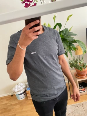 Mörkgrå BOSS t-shirt i bomull - Snygg mörkgrå t-shirt från BOSS med diskret logga på bröstet. Klassisk rund halsringning och korta ärmar. Tillverkad i mjuk bomull som känns skön mot huden. Perfekt basplagg för en clean och stilren look.