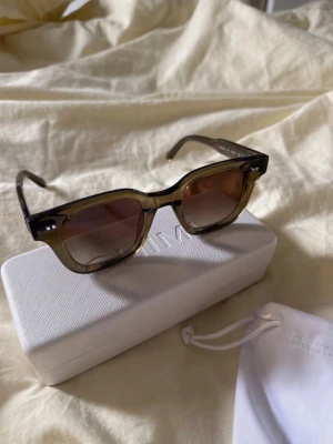 Mörkgröna solglasögon från Chimi - Snygga solglasögon från Chimi med rektangulära bågar i transparent brun plast. Perfekta för dig som vill ha en trendig accessoar till sommaren. Solglasögona är använda men har fortfarande mycket att ge, skick 7/10. 