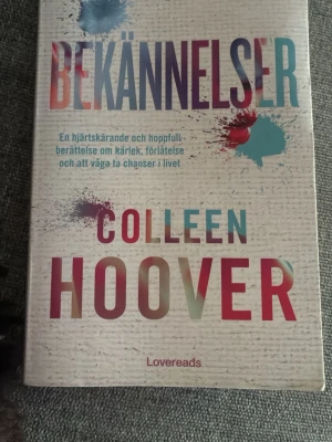 Bekännelser av Colleen Hoover - Bekännelser är en gripande roman av Colleen Hoover. Omslaget är vitt med färgstänk i blått, rött och lila och titeln är tryckt i stora bokstäver. Boken handlar om kärlek, förlåtelse och att våga ta chanser i livet. Pocketutgåva från Lovereads.