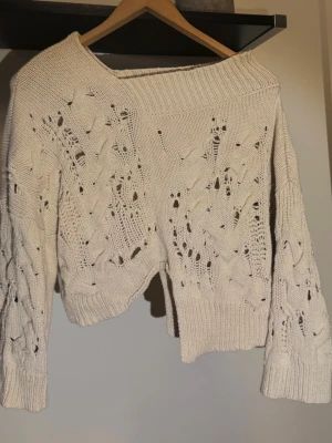Unik vit stickad tröja  - Trendig vit stickad tröja från Rohe med bred ribbad krage och unikt hålmönster. Tröjan har vida ärmar och är gjord i ett mjukt material. Passar dig som gillar en avslappnad men ändå stilren look. OBS bild 4, några trådar är lösa som i bilden men annars bra, använt skick.