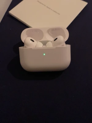 Apple AirPods Pro trådlösa hörlurar - Säljer ett par Apple AirPods Pro med laddningsetui. De är vita och har en stilren, kompakt design med silikonpluggar för bästa passform. Perfekta för musik, samtal och träning. Levereras med originaltillbehör som laddkabel och extra öronproppar.
