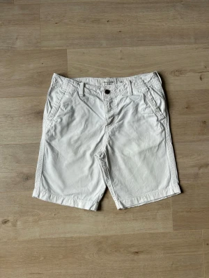 Vita Abercrombie & Fitch Chinosshorts Shorts Storlek W34 - Mycket fina Abercrombie & Fitch shorts i vit färg | Jeansen är i mycket bra skick och sparsamt använda. |  Äkta som allt annat jag säljer! ✅ |  Storlek: W34 | Skick: Mycket Bra Skick-  har tyvärr några väldigt små fläckar (SE SISTA BILD) | Färg: Vit | Märke: Abercrombie & Fitch| Modell: Shorts |   Hör gärna av dig vid frågor så svarar jag så fort jag kan! 😁 |  (SKU - 175)