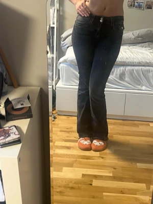Svarta bootcut jeans med vita sömmar - Snygga svarta bootcut jeans med markerade vita sömmar och klassisk femficksdesign. Jeansen har en lätt tvättad look och stängs med dubbla knappar och dragkedja. Stockholmsstil och perfekt för små fester men också en casual look. 