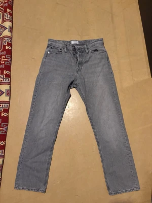 Grå relaxed jeans från Jack & Jones - Snygga grå jeans från Jack & Jones i relaxed fit-modellen Chris. Klassisk femficksdesign, raka ben och hög midja. Perfekta för en avslappnad och trendig look. Tillverkade i bomull för skön känsla hela dagen.