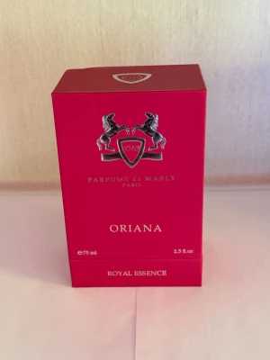Parfums de Marly Oriana 75ml - Lyxig parfym från Parfums de Marly i serien Royal Essence. Oriana kommer i en elegant, djuprosa kartong med silverdetaljer och logotyp med två hästar. Flaskan innehåller 75 ml och doften är exklusiv och modern.