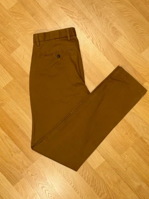 Chinos från GAP – Storlek 32/34  - Säljer ett par snygga chinos från GAP i en klassisk brun färg. De är i fint skick och passar perfekt till både vardags och finare tillfällen.  Märke: GAP  Storlek: 32/34  Material: 98% bomull, 2% spandex (stretchiga och bekväma)  Skick: Mycket bra skick, sparsamt använda. Hör gärna av dig om du har några frågor eller vill ha fler bilder! 