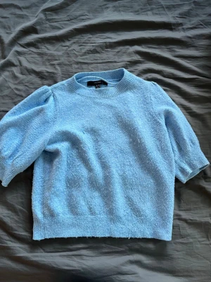 Ljusblå puffärmad stickad tröja H&M - Mysig ljusblå stickad tröja från H&M med puffärmar och ribbade muddar. Tröjan har en rund halsringning och är gjord i ett mjukt, fluffigt material som känns skönt mot huden. Perfekt för dig som gillar en söt och trendig look.