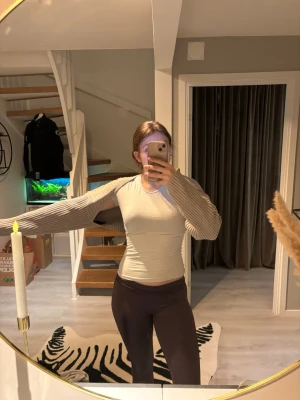 Beige ribbstickad bolero - Trendig beige bolero med ribbstickade ärmar och öppen front. Perfekt att slänga över en topp för en cool lager-på-lager-look. Ärmarna är långa och materialet känns mjukt och stretchigt. Enkel att matcha med olika outfits.