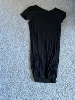 Svart ribbad kortärmad klänning  - En svart, ribbad kortärmad klänning från XOXO Friends. Modellen är kroppsnära och har en enkel, rund halsringning. Perfekt för dig som gillar en stilren och basic look.