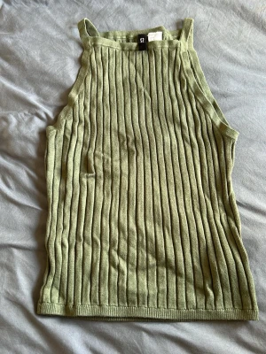 Ljusgrön ribbad linnetopp HM - Snygg ljusgrön ribbad linnetopp med raka axelband och ärmlös design. Toppen har en tight passform och är tillverkad i ett stickat material som ger en trendig look. Perfekt att matcha med jeans eller kjol för en cool stil.