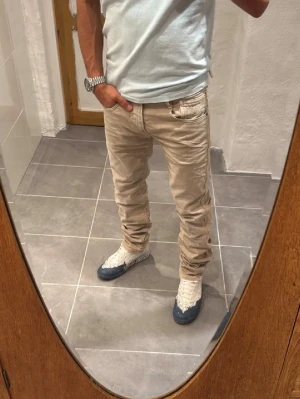 Beiga slim fit jeans - Snygga beiga slim fit jeans med klassisk femficksdesign och låg midja. Jeansen har raka ben och är tillverkade i ett mjukt bomullsmaterial med lite stretch för extra komfort. Perfekta för en avslappnad och trendig look.