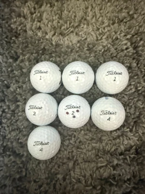 7 vita Titleist golfbollar - Säljer sju stycken vita golfbollar från Titleist, modell Tour Soft. Bollarna har olika nummer (1, 2, 4) och är tillverkade i slitstarkt material med klassisk dimple-design. Perfekta för dig som vill fylla på golfbagen med kvalitetsbollar nu inför sommaren!