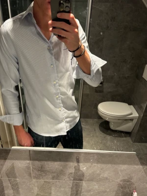 Vit och blårandig skjorta  - Riktigt snygg skjorta med blåa och vita ränder i storlek M. Den är i riktigt bra skick och passar perfekt nu till sommaren. Jag på bilden är 188cm och bär storlek M. Hör av er vid fler funderingar:)