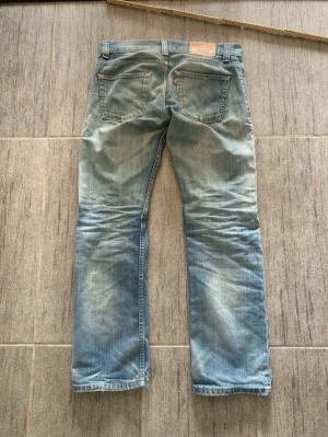Levi's 506 ljusblå raka jeans - Ljusblå raka jeans från Levi's modell 505 med klassiska bakfickor och röd Levi's-tagg. Jeansen har en avslappnad passform och är tillverkade i slitstark denim. Perfekta för en casual look.