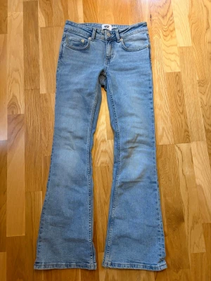 Ljusblå bootcut jeans från 157 - Snygga ljusblå bootcut jeans från 157 med klassisk femficksdesign och utsvängda ben. Jeansen har normal midja och är tillverkade i mjuk denim med en lätt tvättad look. Perfekta för dig som gillar retrostil och vill ha ett par bekväma jeans med cool passform.