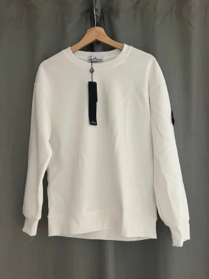 Vit sweatshirt från Stone Island - Vit sweatshirt från Stone Island med klassisk rund hals och ribbade muddar. Köpt på vinted men den var för stor, så säljer vidare!🖤🤍