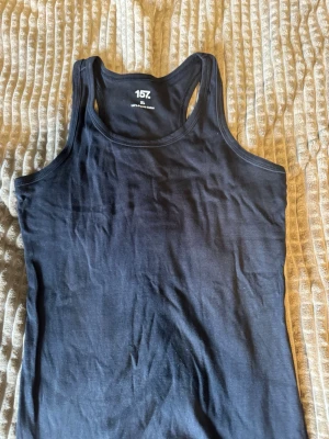 Svart linne och kortbyxa från 157 - Snyggt svart linne från 157 i 100% bomull. Modellen har brottarrygg och är perfekt för en avslappnad och bekväm stil hemma. Enkel design som passar till allt och är supermjuk mot huden.