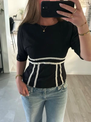 Svart topp med knyt i ryggen - Trendig svart croppad topp från Gina Tricot med vita detaljer och knyt i ryggen❣️Slutsåld på hemsidan!